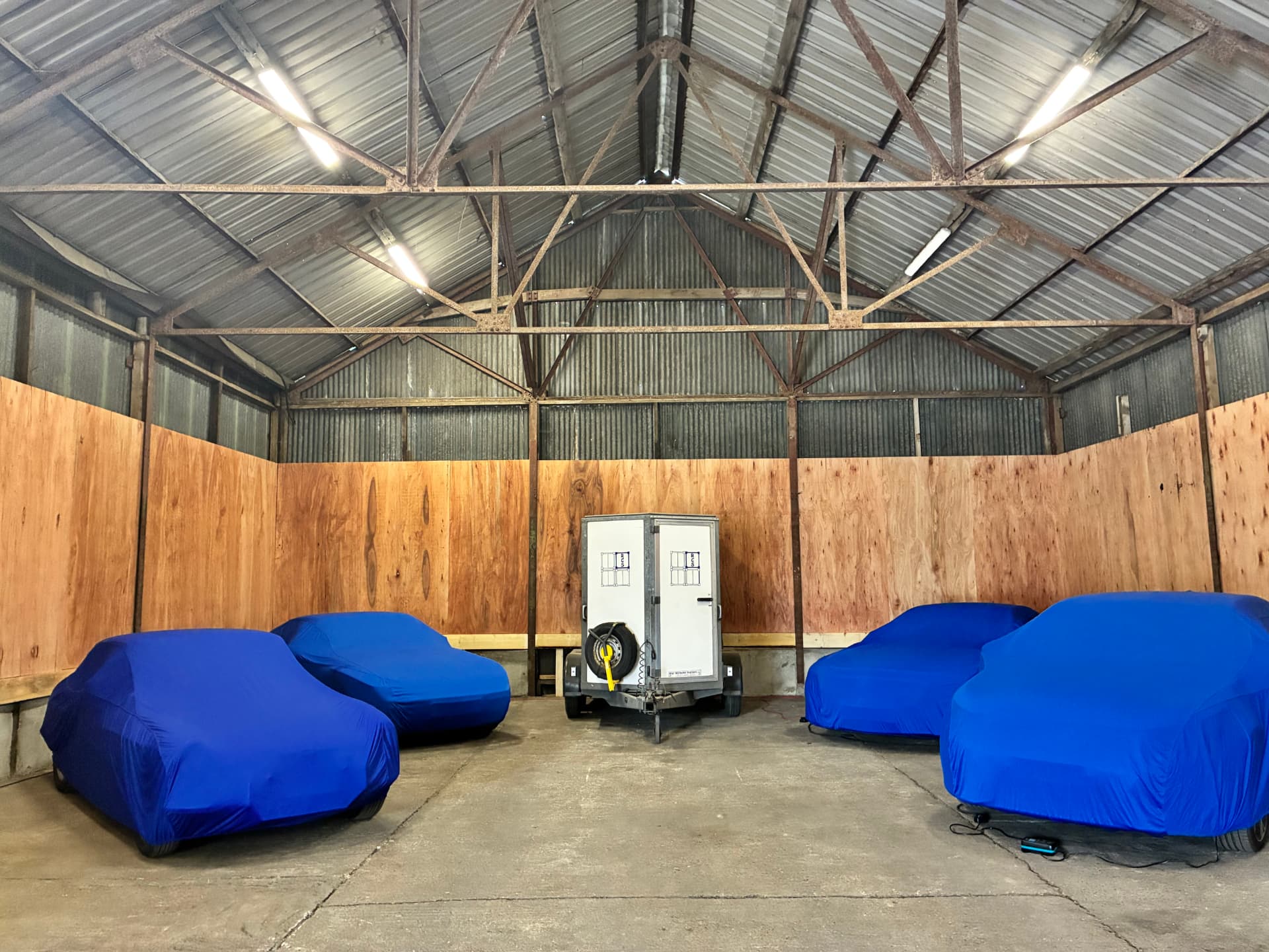 Classic cars under protective covers inside the Madgwick Group secure indoor storage barn in East Sussex